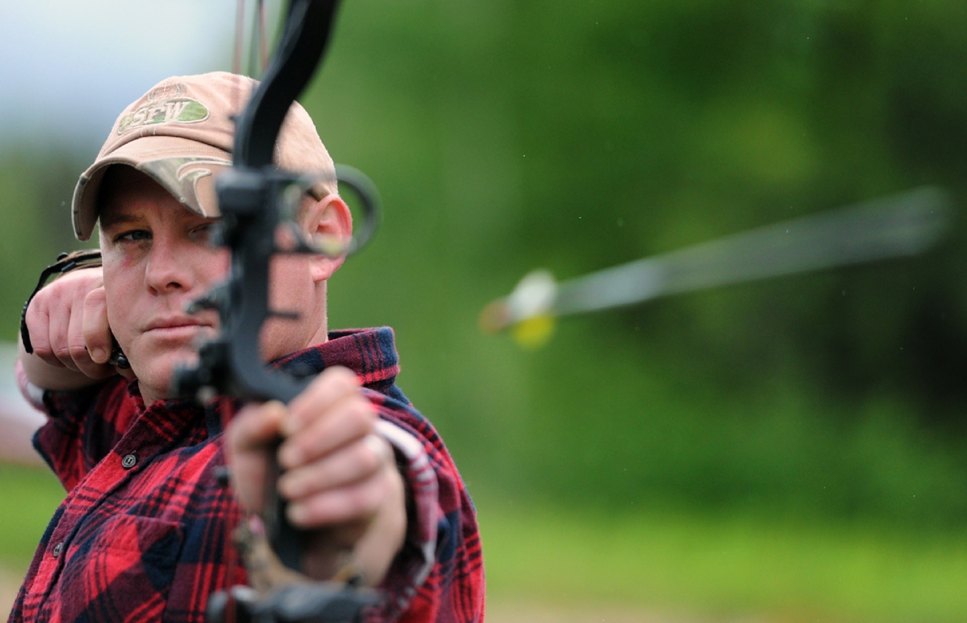 Man in plaid shirt firing an arrow