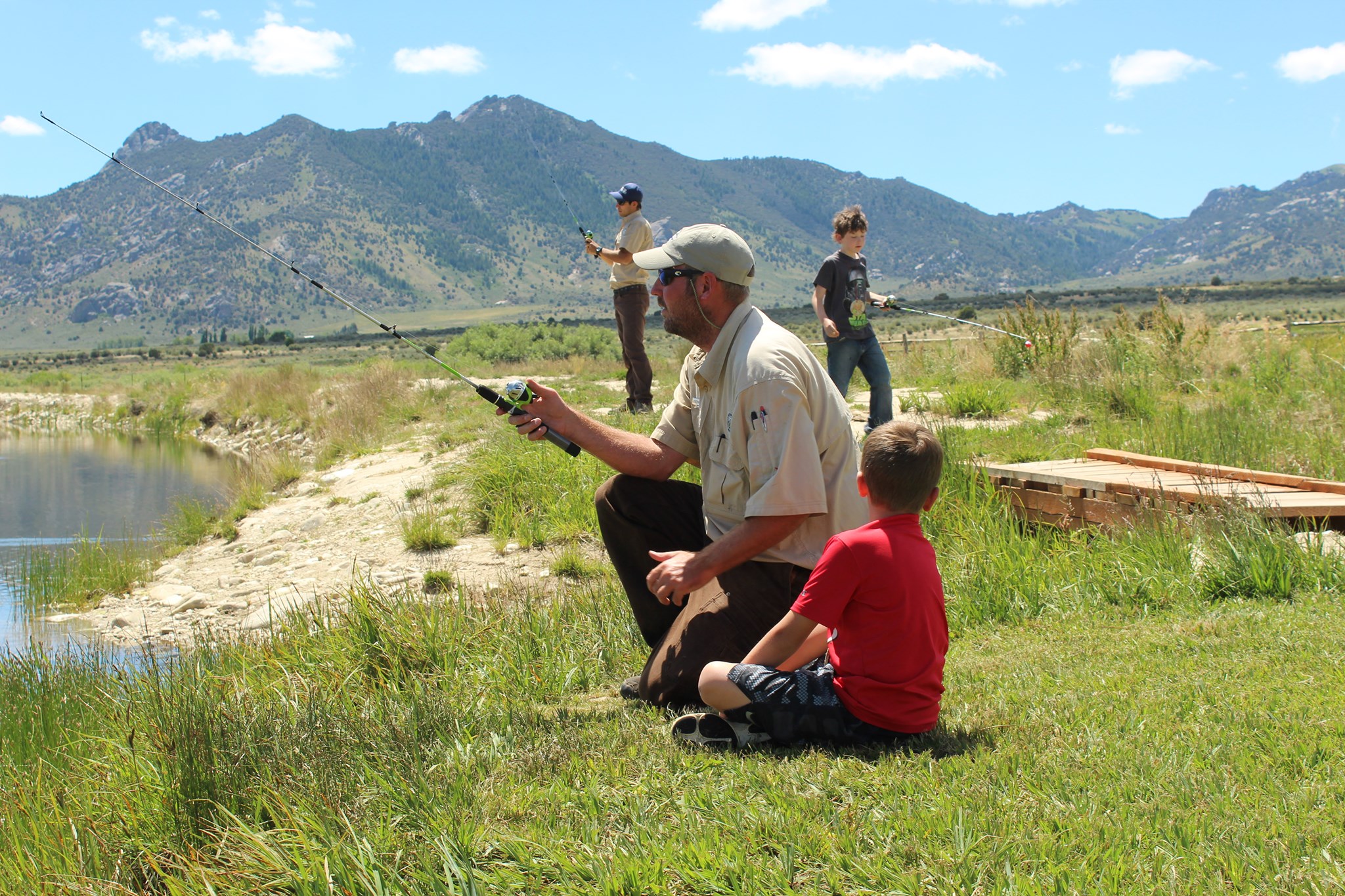 Park rangers teaching children how to fish. Image shows two rangers and two children