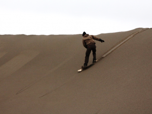 Person sandboarding down the dunes