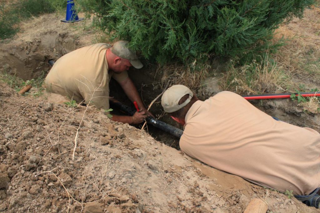 two employees working in trench in the ground