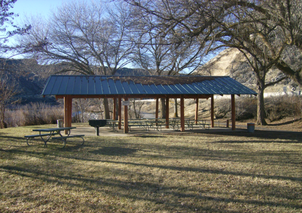 Lower Discovery Shelter. Image of empty shelter in the fall, with leaves on the roof, river in the background