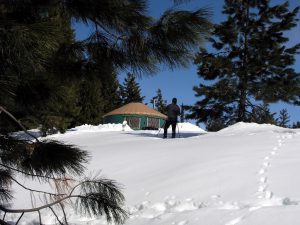 person skiing in front of yurt