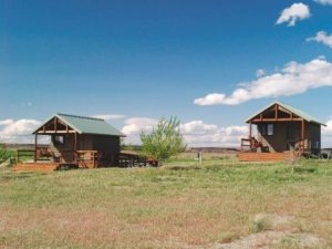 Cabin in the desert, little bits of grass here and there. dunes in the background