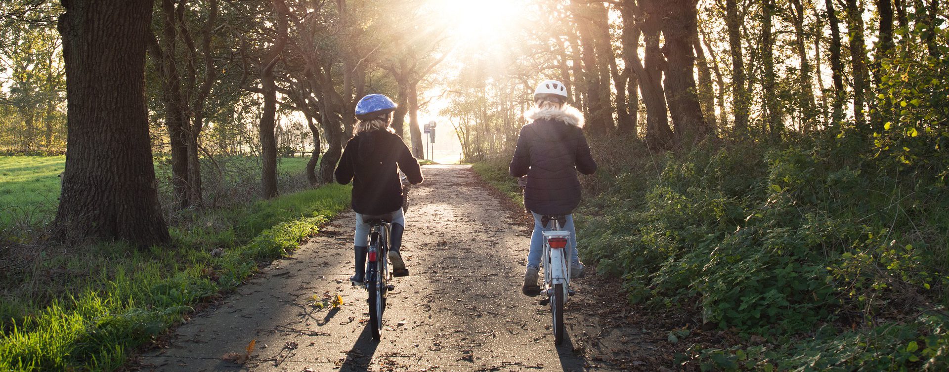 two girls cycling down a forested path