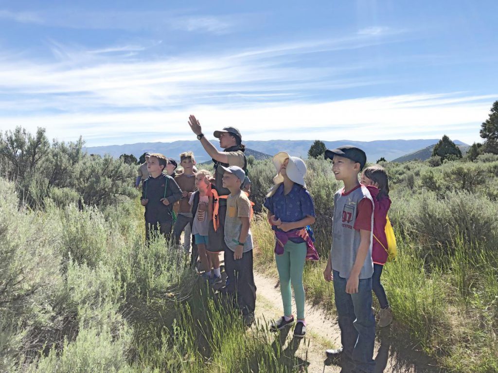 park ranger with a group of kids outisde on a trail