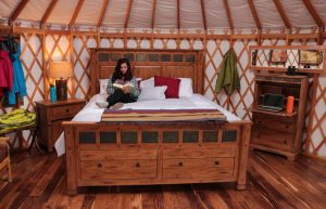 Inside the glamping yurt at Castle Rocks. Woman reading on king sized bed