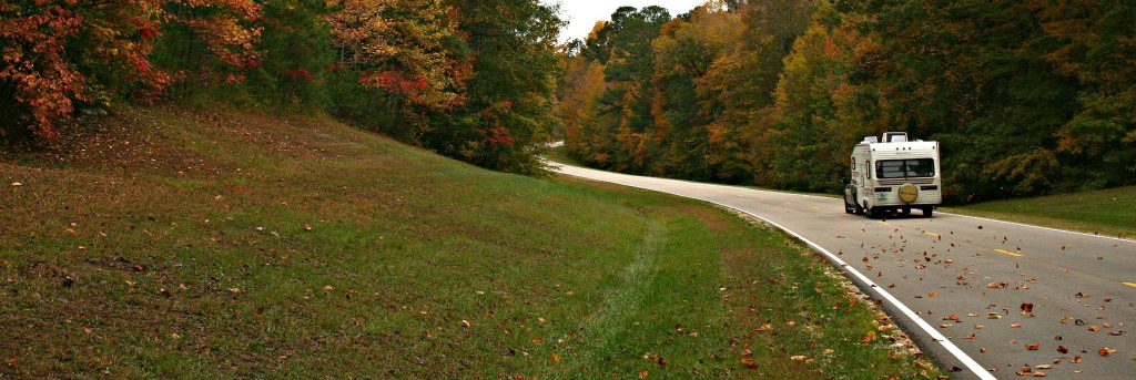 RV driving down a road in fall
