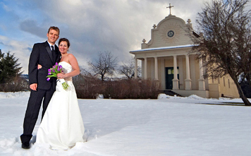 couple in wedding dress and tux in front of old mission