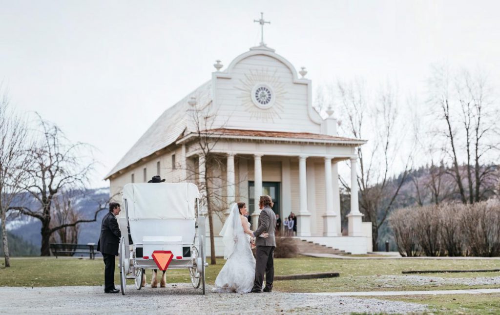 couple posing in front of old mission with a carriage