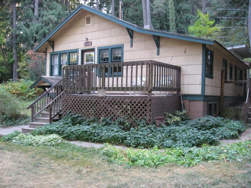 cottage with deck surrounded by trees