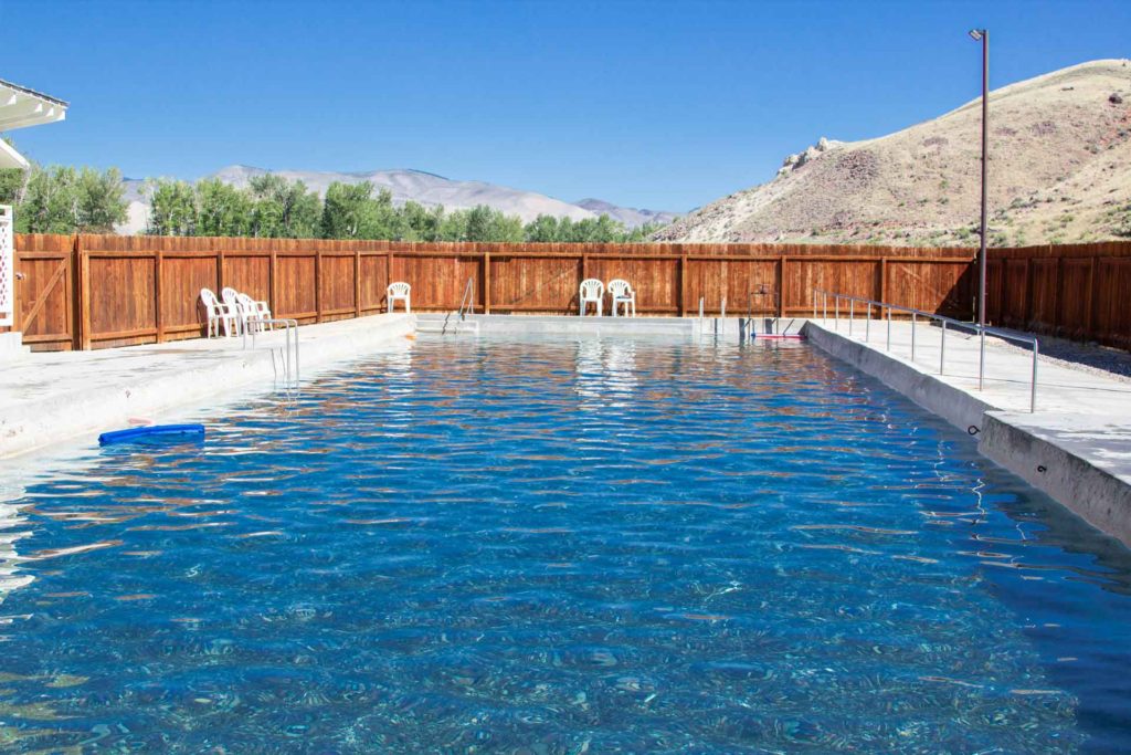 image of pool with white lawn chairs around the edges